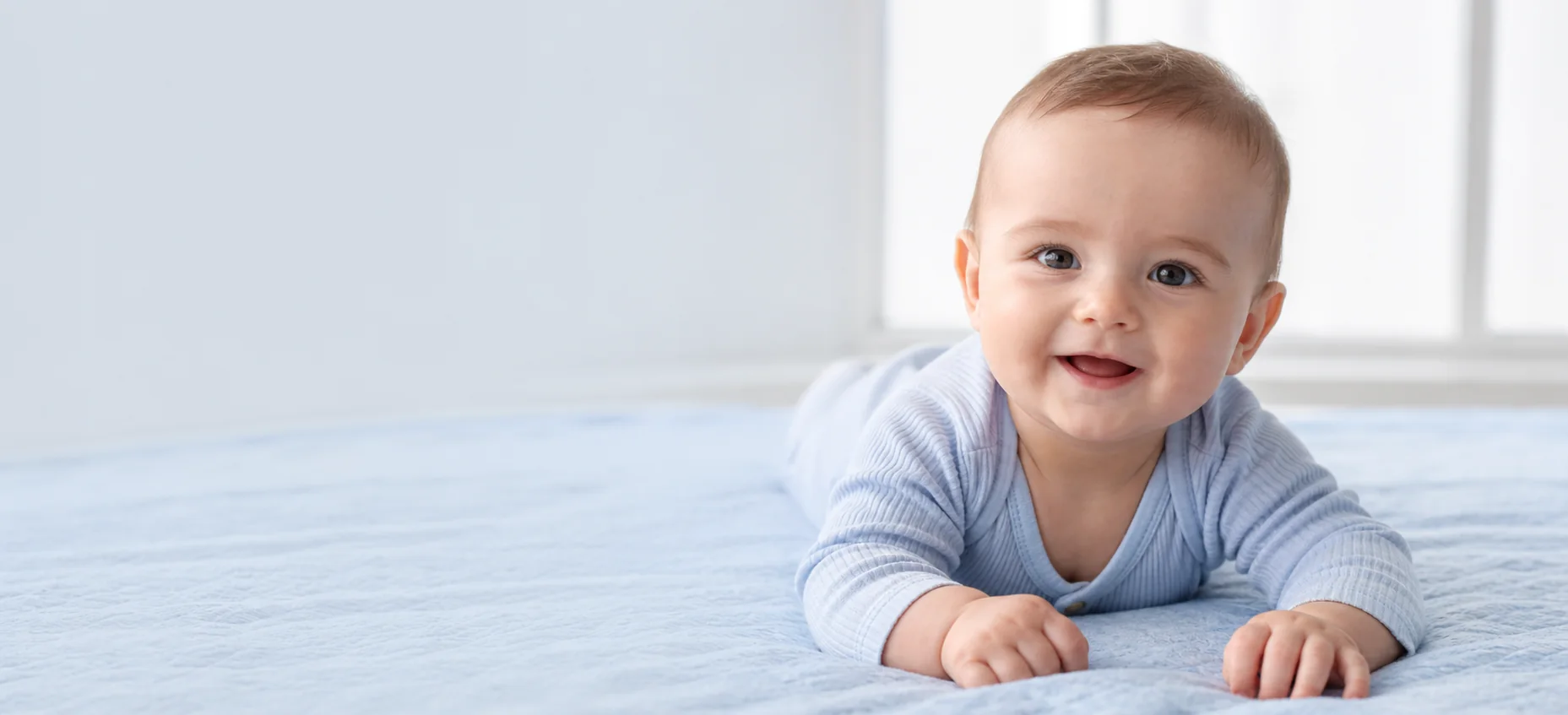 Smiling baby resting safely on a soft blue blanket